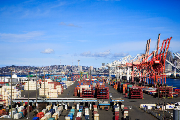A photo taken from a bridge heading to West Seattle showing al he infastructure of cranes and shipping containers in he port of Seattle.
